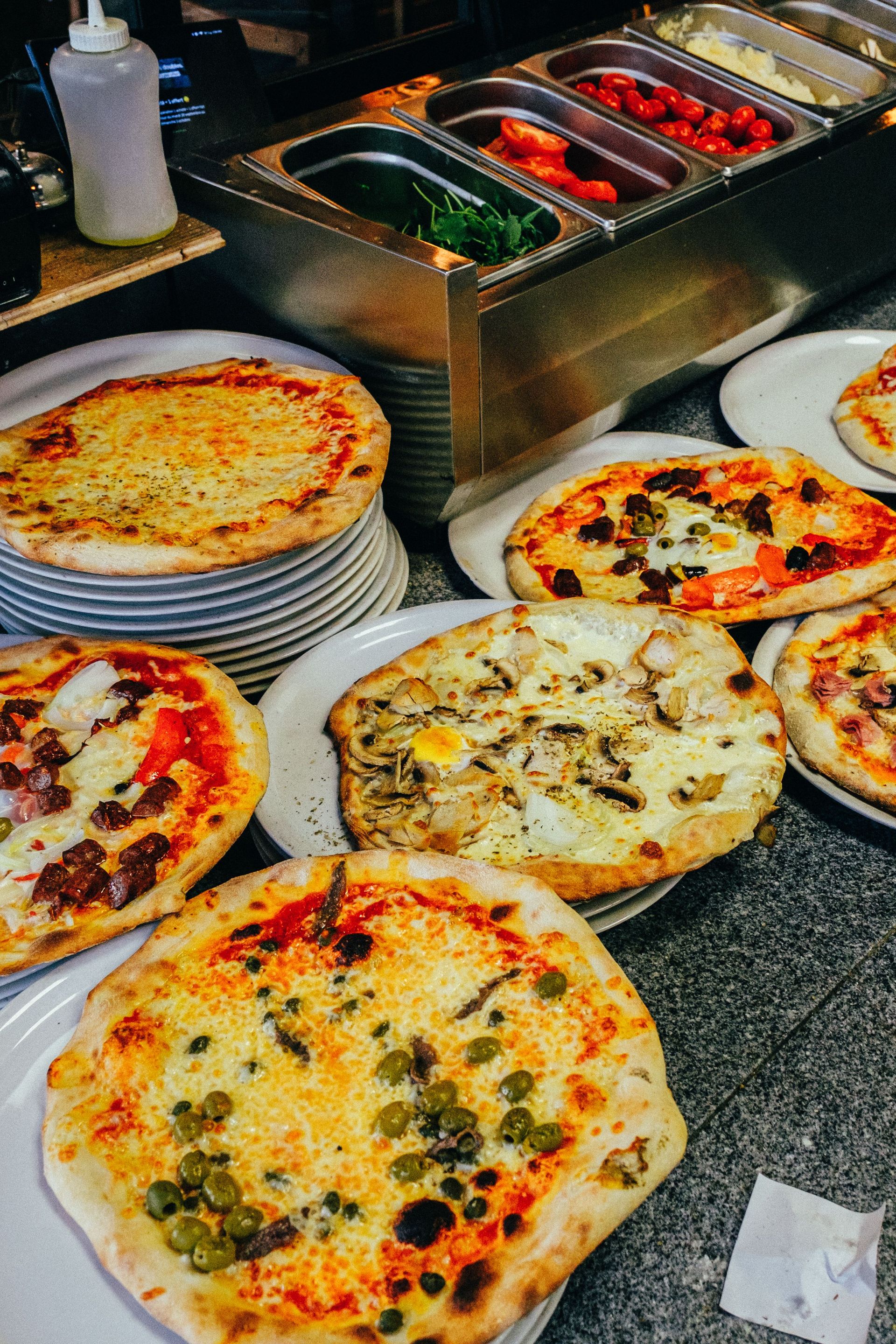 Multiple freshly baked pizzas displayed in a restaurant setting, showcasing assorted toppings.