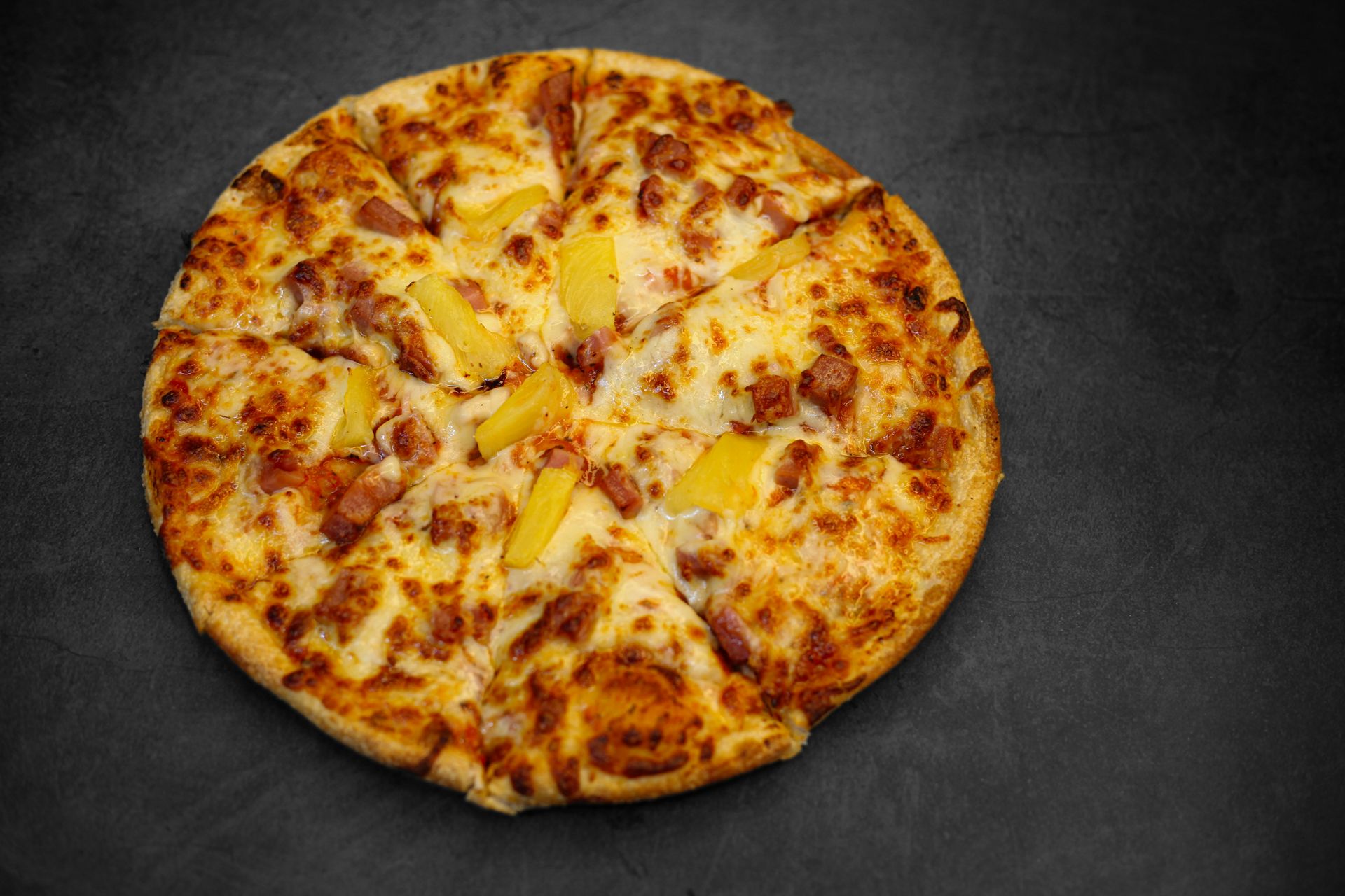A whole pizza with pineapple and meat toppings