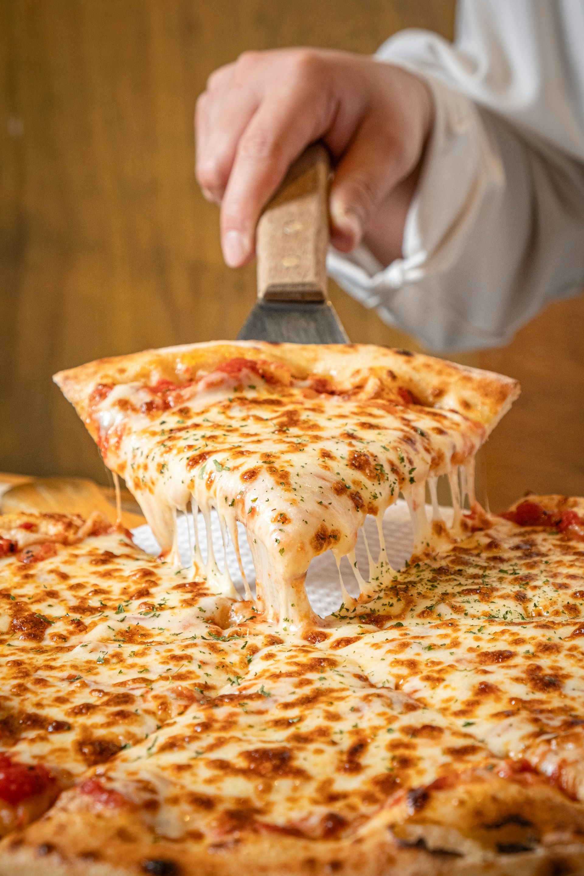 a person cutting a slice of pizza with a pizza cutter
